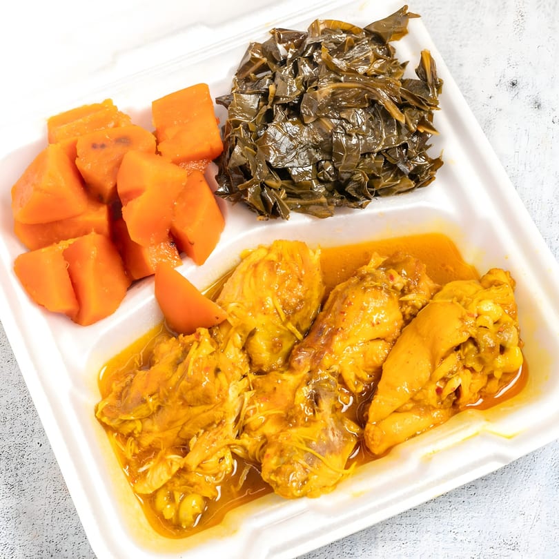 Top Taste Grill's Jamaican curry chicken with steamed callaloo and cubed pumpkin in a takeout container.